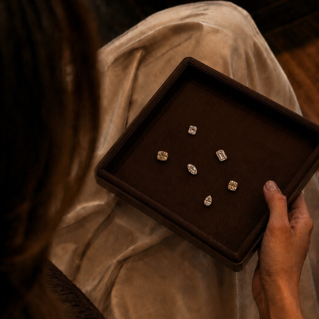 Person holding a brown jewelry tray with diamond earrings.